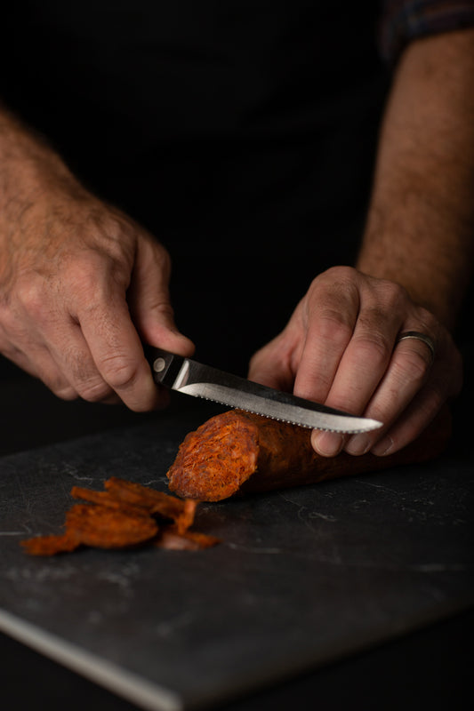 Professional chef cutting bright red spanish chorizo